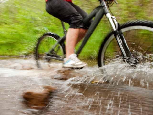 雨の日に自転車をこいで靴が濡れる写真